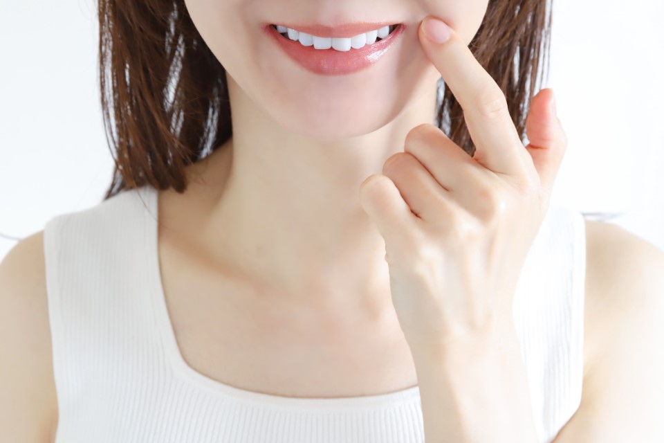 口元を指さす女性